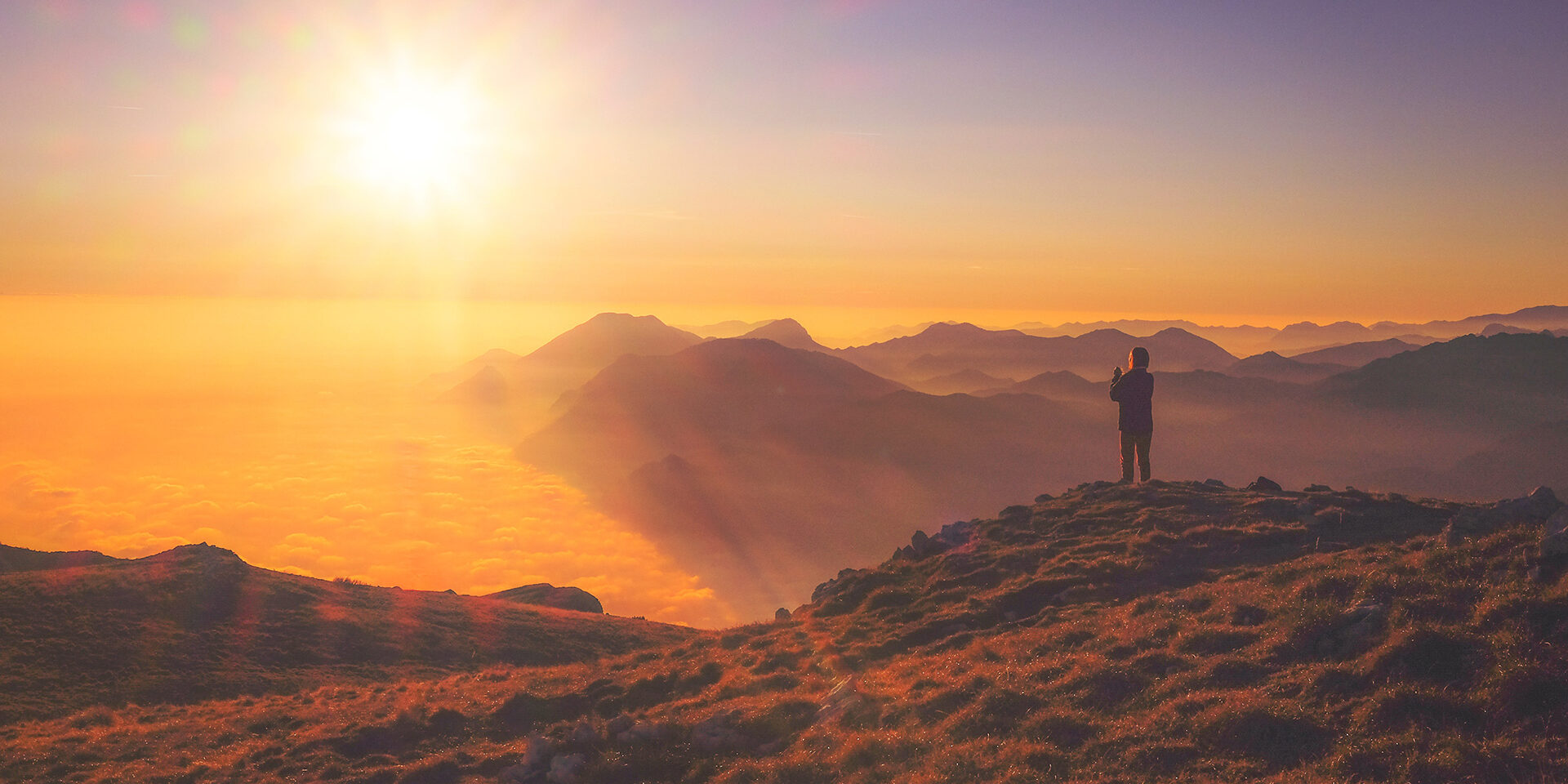 person-standing-on-mountain-at-sunset